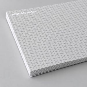 May include: A rectangular notepad with a white paper surface featuring a thin gray grid pattern. The top left corner displays the text MONAD Notes in white capital letters. The stack of paper is thick, showing multiple individual sheets of paper.