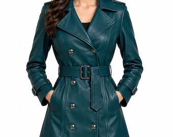 May include: A dark teal double-breasted trench coat made of a smooth material. The coat features a wide notched collar, shoulder epaulets, long sleeves with buckled cuffs, and a matching waist belt with a rectangular buckle. It has six buttons.