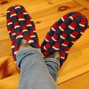 Puede incluir: Un par de zapatillas de punto a rayas rojas, blancas y azules. Las zapatillas las lleva una persona que lleva pantalones vaqueros azules.