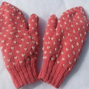 May include: A pair of pink knitted mittens with a white heart pattern.