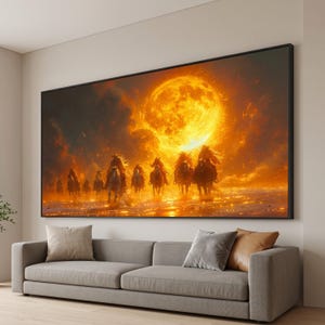 Könnte beinhalten: Ein rechteckiger Wandkunstdruck in einem schwarzen Rahmen, der eine Gruppe von Reitern auf Pferden zeigt, die sich unter einem großen, leuchtenden orangefarbenen Mond durch eine Landschaft bewegen. Die Szene ist voller warmer Gold- und Orangetöne.