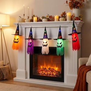 Puede incluir: Una guirnalda de cinco decoraciones de fantasmas colgantes, cada una con un sombrero de bruja negro con una banda colorida. Los fantasmas están iluminados en naranja, morado, blanco, verde y rojo, con expresiones faciales impresas en negro.