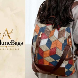 Puede incluir: Una mochila con un patrón geométrico de cubos en naranja, azul, rojo y beige. El bolso tiene adornos de cuero sintético marrón, cremalleras doradas y correas ajustables. El texto AveluneBags Timeless Elegance aparece en el lado izquierdo.