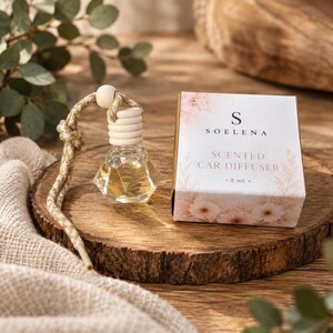May include: A glass car diffuser with a faceted base, a light wood cap, and a braided hanging cord, accompanied by a white cardboard box labelled SOELENA SCENTED CAR DIFFUSER 8 ml with a soft pink floral print on the packaging.
