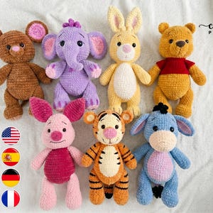 Könnte beinhalten: Eine Sammlung von sieben gehäkelten Plüschtieren, darunter eine braune Maus, ein violetter Elefant, ein gelber Hase, ein goldener Bär mit rotem Oberteil, ein rosa Ferkel, ein orangefarbener Tiger und ein blauer Esel. Enthält ein PDF-Häkelmuster-Symbol.