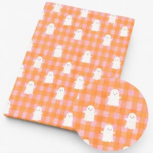 May include: A rectangular fabric sheet featuring a repeating pattern of small white ghosts with simple black eyes and mouths, set against a vibrant orange and light pink checkered gingham background, with a circular inset showing the same pattern.