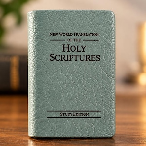 Puede incluir: Un libro de color verde salvia con una cubierta texturizada que presenta el texto impreso en negro New World Translation of the Holy Scriptures y Study Edition. El libro es rectangular, de orientación vertical y con un grano marcado.