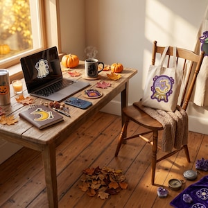 Puede incluir: Un escritorio de madera con un portátil con pegatina de fantasma, un vaso decorado con calabaza, un cuaderno con pegatina de luna creciente, una taza, una bolsa con gráfico de bola de cristal en una silla y un delantal con estampado de caldero.