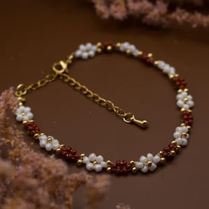 Pulseira de contas com flores em tom bordô e corrente extensora banhada a ouro 18k.