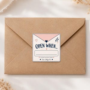 May include: A square sticker on a brown kraft paper envelope. The sticker features a pink envelope graphic, the text "OPEN WHEN..." above a blank line, and the phrases "a little love from home" and "Dear College Kid" with heart icons.