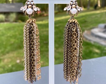 May include: A pair of gold and silver chain tassel earrings with a clear rhinestone and pearl bee charm at the top.