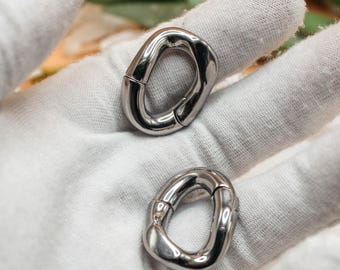 May include: Two silver-toned metal carabiner rings with a smooth, polished finish. Each ring features an oval shape with a spring-loaded gate mechanism, allowing the loop to open and close securely for attachment purposes.