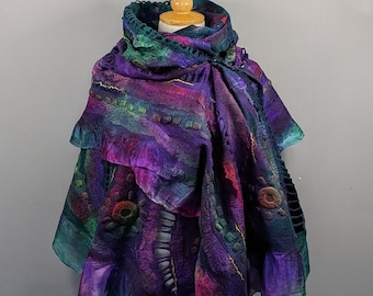 Può includere: Una sciarpa di lana feltrata viola, verde e rosa con un bordo arricciato e ricami intricati. La sciarpa è drappeggiata su un manichino di legno.