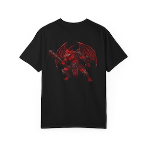 May include: A black short-sleeved t-shirt featuring a graphic print on the back. The design depicts a red, winged demon-like creature in a crouched stance, holding a dark, textured club-like weapon while wearing armoured plating and a loincloth.