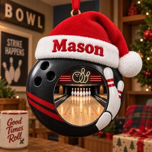 May include: A black bowling ball ornament featuring a red Santa hat with the name Mason embroidered in red on the white fur trim. The center of the ball displays a circular cutout showing a bowling alley lane with pins and a neon bowling graphic.