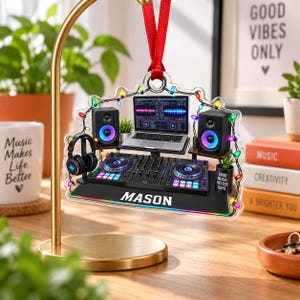 Puede incluir: Un adorno de acrílico transparente con un diseño impreso de equipo de DJ que incluye portátil, altavoces, auriculares y consola de mezclas. Incluye luces de colores y el nombre MASON impreso en blanco sobre una base negra con borde arcoíris.