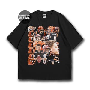 Op de afbeelding: Een zwart t-shirt met korte mouwen en een grafische print van Joe Burrow in verschillende football-houdingen en spelacties. De tekst "JOE BURROW" is gedrukt in grote oranje en witte blokletters aan de linkerkant van het grafische ontwerp.