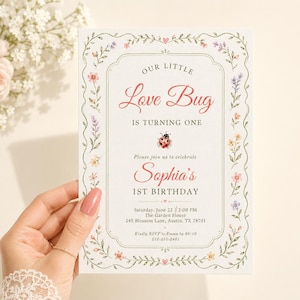May include: A rectangular birthday invitation card featuring a floral border with small pink, purple, and yellow flowers. The text reads: Our Little Love Bug Is Turning One, Sophia's 1st Birthday, with event details including date, time, and location.