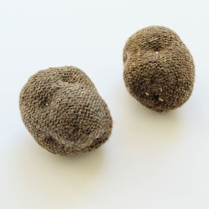 Peut inclure: Deux pommes de terre tricotées brunes. Les pommes de terre sont faites d'un matériau doux et texturé et ont une surface légèrement bosselée.