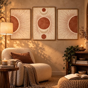 May include: A set of three rectangular wall art prints featuring a sun and moon motif in terracotta and cream tones. The central piece displays a full sun with crescent moons, while the two side pieces show half-sun designs with radiating lines.