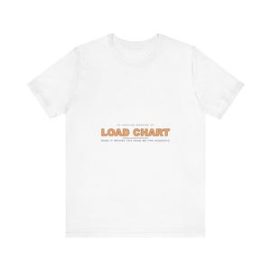 May include: A white short-sleeve t-shirt featuring the text "CERTIFIED OPERATOR" in small black letters above the orange words "LOAD CHART" and the smaller black text "READ IT BEFORE YOU READ ME THE SCHEDULE" centered on the chest.