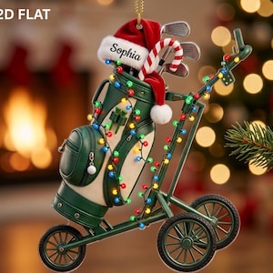 May include: A 2D flat Christmas ornament shaped like a green golf bag on a cart, decorated with a string of multicolored lights, a candy cane, and a red Santa hat featuring the name Sophia. The golf bag contains several golf clubs.