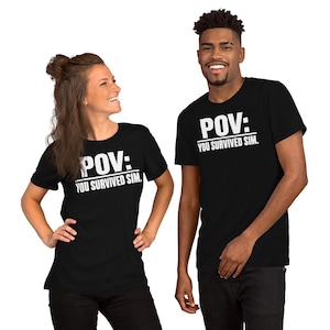 May include: A black short-sleeved t-shirt featuring white text printed on the chest that reads "POV: YOU SURVIVED SIM." The shirt has a crew neckline and a standard fit, constructed from a solid black fabric with bold, high-contrast white lettering.