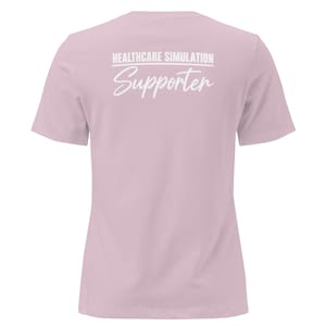 May include: A light pink short-sleeved t-shirt featuring white text on the back that reads HEALTHCARE SIMULATION in a bold sans-serif font above the word Supporter written in a white cursive script with a horizontal line separating them.