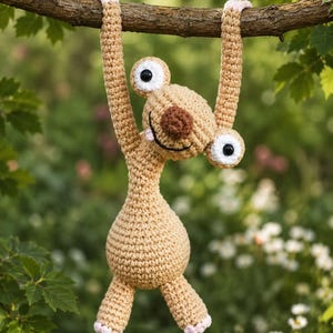 Peut inclure: Un paresseux en crochet beige avec de longs bras suspendus à une branche. La créature a une tête ronde, un nez marron foncé, une bouche noire brodée et deux grands yeux blancs avec des pupilles noires. Les mains et les pieds ont des touches rose clair.