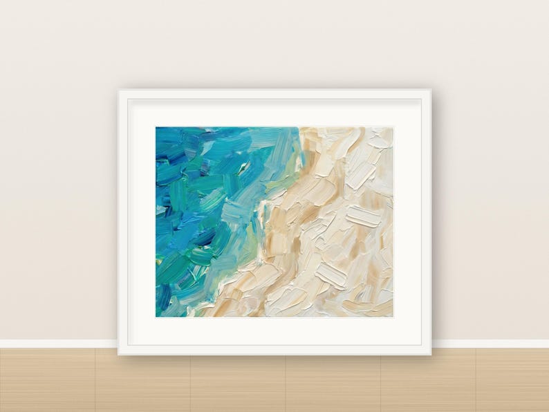 May include: An oil painting in a white frame featuring thick, textured brushstrokes of blue and turquoise ocean waves meeting a sandy beige shoreline. The artwork displays a high-contrast color palette with visible impasto paint application.
