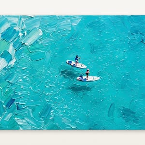 K&ouml;nnte beinhalten: Ein &Ouml;lgem&auml;lde auf Leinwand, das zwei Personen auf Stand-Up-Paddleboards in leuchtend t&uuml;rkisfarbenem Wasser zeigt. Das Kunstwerk zeichnet sich durch dicke, strukturierte Pinselstriche aus, die Bewegung auf der blauen Meeresoberfl&auml;che erzeugen.
