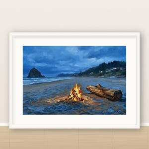 May include: A framed landscape print depicting a beach at twilight with a bright orange campfire burning in the sand. A large piece of driftwood lies nearby, with a dark sea, a rocky monolith, and a distant coastline visible under a blue sky.