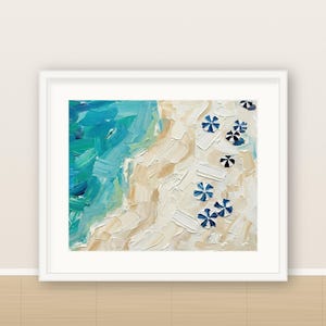 May include: An oil painting in a white frame depicting an aerial view of a beach with thick, textured brushstrokes. The scene features vibrant turquoise and blue ocean waves meeting a sandy beige shore dotted with small, blue and white striped umbrellas.