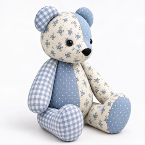 May include: A stuffed teddy bear constructed from patchwork fabric featuring a mix of light blue and white patterns. The design includes blue gingham, white fabric with small blue floral prints, and light blue fabric with white polka dots.