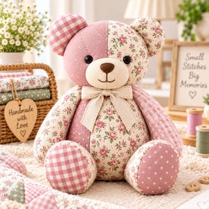 May include: A stuffed teddy bear crafted from various fabric patches, featuring a mix of dusty pink, cream, and floral patterns. The bear has a beige muzzle, a brown nose, black eyes, and a cream-coloured ribbon tied around its neck.