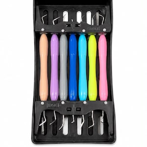 Puede incluir: Un juego de siete herramientas de manualidades con mangos de colores melocotón, morado, gris, azul, azul claro, amarillo y rosa, organizadas en una bandeja de almacenamiento de plástico negro. Cada herramienta tiene una punta de gancho metálica.