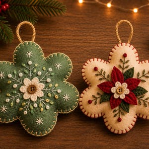 May include: Two felt ornaments shaped like six-petaled flowers with hanging loops. One is sage green with white floral embroidery and a central button. The other is cream with a red poinsettia applique, green leaves, and a central button.