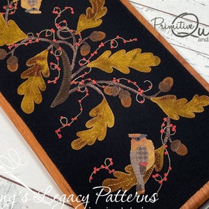 May include: A black felt mat with a brown wooden frame, featuring an embroidered design of two birds perched on a branch with oak leaves and berries. The mat is 10 inches by 20 inches and is titled "Duet".