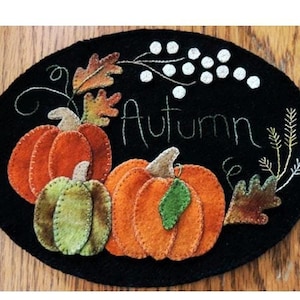 May include: A black felt oval with an embroidered design of three pumpkins, leaves, and the word "Autumn".