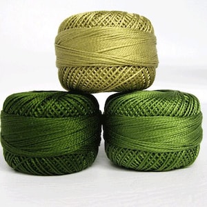May include: Three spools of thread, one green and two shades of green.