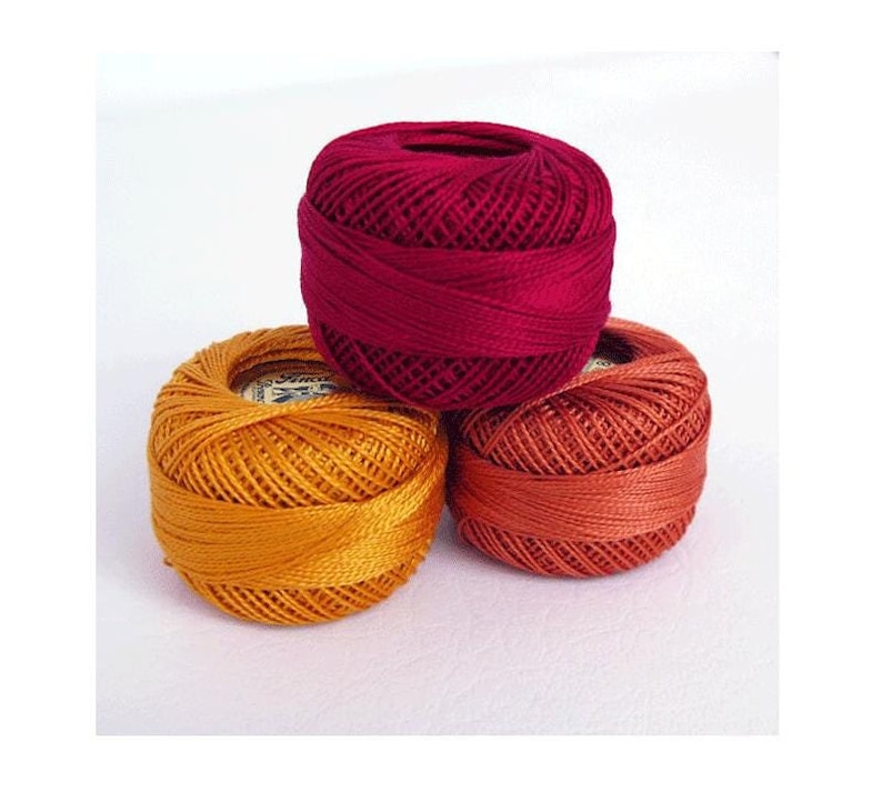 May include: Three balls of embroidery floss in shades of red, orange, and yellow.