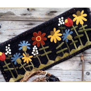 May include: A black wool runner with a colorful appliqué design of flowers. The flowers are red, yellow, blue, and green. The runner is perfect for adding a touch of whimsy to any home.