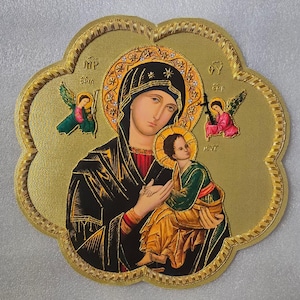 May include: A gold-toned, flower-shaped icon featuring a central depiction of a figure in a black head covering holding a child in green and gold robes. Two small winged figures are positioned on either side, with Greek lettering visible.
