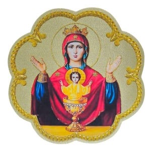 May include: A decorative plaque featuring a religious icon of a crowned figure in a red and blue robe with hands raised, holding a small child in a yellow garment inside a golden chalice, all framed by a scalloped edge with gold embroidery.