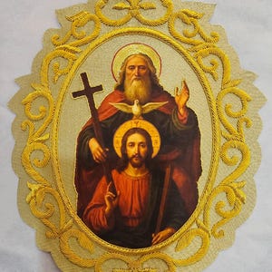 以下が含まれることがあります： 神父、鳩の姿をした聖霊、十字架を持つイエス・キリストからなる三位一体が中央に描かれた楕円形の宗教的なワッペン。画像は、精巧で立体的な金色の刺繍で縁取られています。