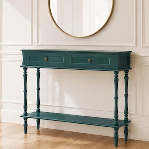 May include: A dark teal console table featuring two rectangular drawers with small round brass-toned knobs. The table is supported by four slender, turned legs and includes a lower shelf for storage, all finished in a matte teal paint.