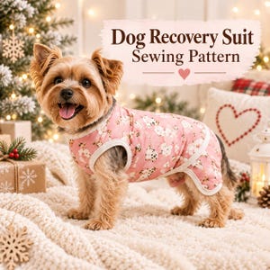 May include: A small dog wearing a pink recovery suit with a white floral pattern. The suit features white trim around the neck and leg openings. The text 'Dog Recovery Suit Sewing Pattern' with a small heart icon is displayed above the dog.