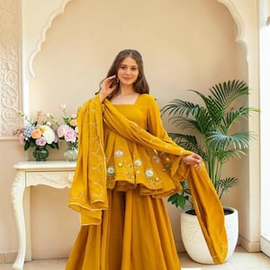 Può includere: Un completo a tre pezzi color giallo senape composto da un top peplum con scollo quadrato, ricami floreali e decorazioni circolari, una gonna lunga fino ai piedi e una sciarpa lunga e leggera con bordo smerlato bianco.