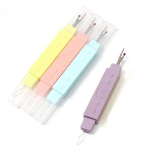 May include: Four seam rippers with pastel-colored plastic handles in yellow, pink, light blue, and purple. Each tool features a metal blade with a red safety ball at the tip, a clear protective cap, and a thin wire loop at the base of the handle.