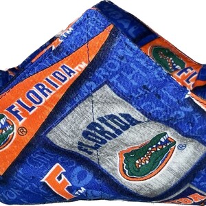 May include: A blue and orange fabric bowl with a repeated pattern of the University of Florida Gators logo and the word "Florida".